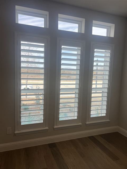 Plantation shutters on tall windows with transoms